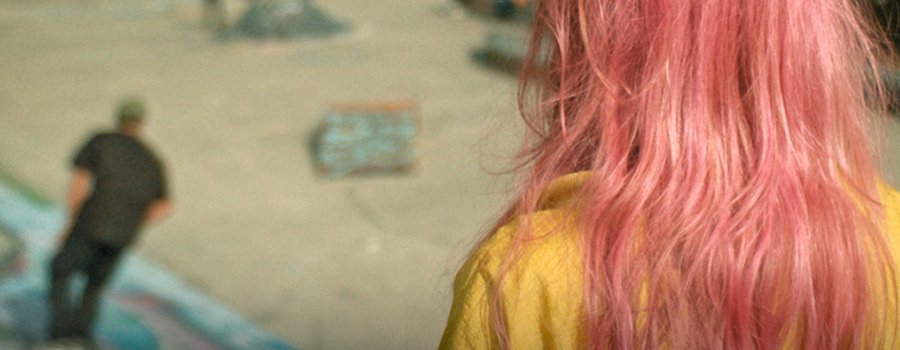 La chica del cabello rosa y una patineta al hombro